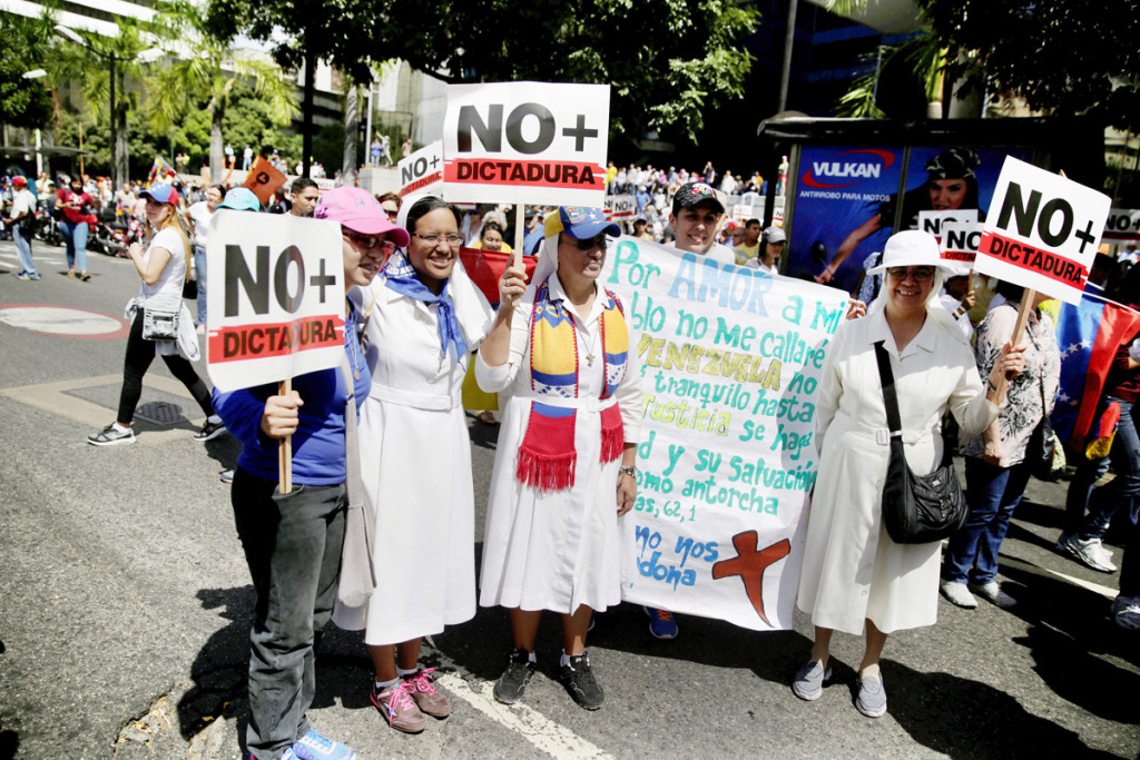 Nuns hold placards reading "No More Dictatorship" during an opposition rally April 6 in Caracas, Venezuela. In response to a renewed constitutional crisis in the country, the Venezuelan bishops' conference has called for 'peaceful civil disobedience" to restore constitutional order. (CNS photo/Marco Bello, Reuters) See VENEZUELA-CRISIS-BISHOPS April 6, 2017.